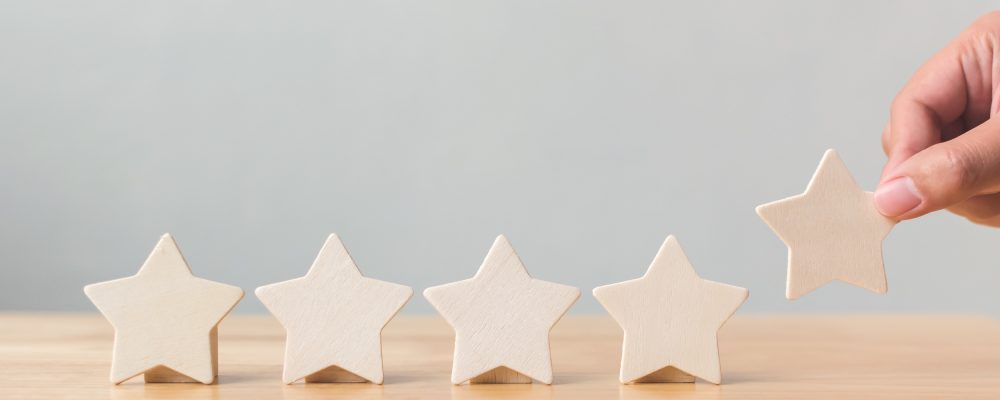 Hand putting wooden five star shape on table. The best excellent business services rating customer experience concept