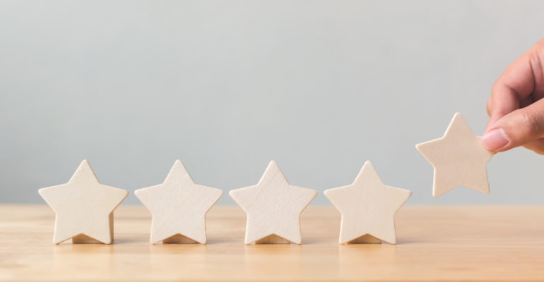 Hand putting wooden five star shape on table. The best excellent business services rating customer experience concept