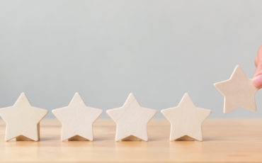Hand putting wooden five star shape on table. The best excellent business services rating customer experience concept