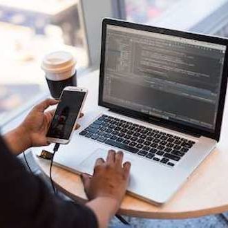 person-looking-at-phone-and-at-macbook-pro-1181244